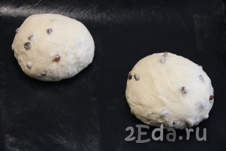 Тесто поднимется и округлится. Обмять тесто, разделить на две части и сформировать два круглых хлеба. Выложить домашний хлеб с изюмом на противень, застеленный ковриком для выпечки (или пергаментом).