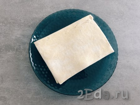 Замороженное дрожжевое слоёное тесто достать из морозилки и разморозить его при комнатной температуре. 