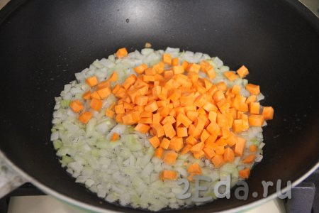 Затем в сковороду добавить морковь, нарезанную на мелкие кубики, перемешать с луком. Обжаривать овощи, периодически перемешивая, минут 5.
