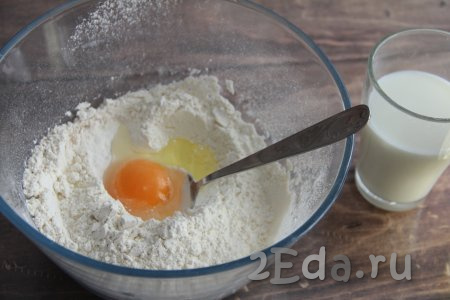 В получившуюся смесь из муки, дрожжей и сахара влить 200 миллилитров молока, предварительно подогретого до 40 градусов, добавить яйцо.