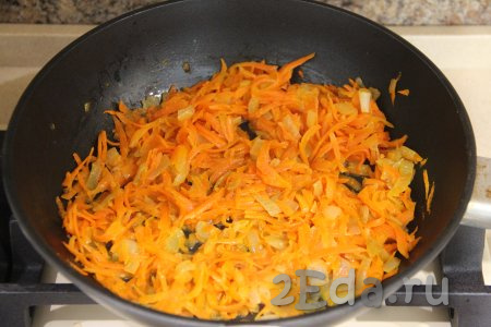 К луку, обжарившемуся до золотистости, выложить натёртую на крупной тёрке морковку, перемешать овощи и обжаривать их вместе, иногда перемешивая, до мягкости моркови (минут 7-8). Затем убрать обжаренные овощи с огня и дать им остыть.