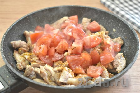 Вымытые помидоры нарезаем на небольшие кубики, добавляем на сковороду, всыпаем специи (у меня - приправа для мяса), перемешиваем, обжариваем свинину с овощами 2 минуты.