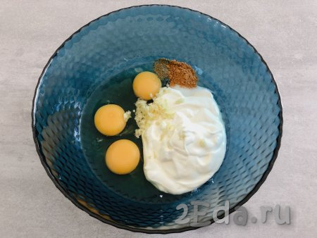 Тем временем в глубокой посуде соединяем 150 грамм сметаны, 3 яйца, соль, пропущенный через пресс чеснок, чёрный молотый перец и мускатный орех.