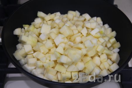 Яблоки почистить, срезая кожуру и удаляя семечки, затем нарезать на мелкие кубики, выложить в сковороду, посыпать 30 граммами сахара, полить 20 миллилитрами лимонного сока, перемешать и поставить на средний огонь. 