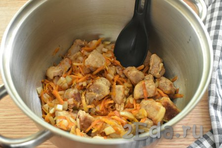 Обжаренные кусочки свинины с овощами со сковороды перекладываем в глубокую кастрюлю с толстым дном.