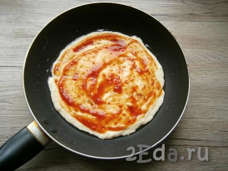 Холодную сковороду смазать растительным маслом. Выложить тесто и разровнять его по дну сковороды. Смазать тесто томатным соусом.