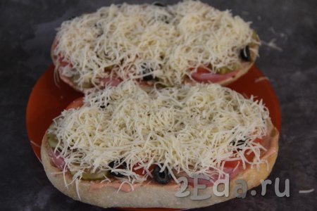 Пиццу из батона щедро посыпать сыром, натёртым на мелкой тёрке.