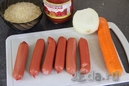 Подготовить продукты для приготовления риса с сосисками на сковороде. Сосиски очистить от слюды. Лук и морковь почистить. Рис выложить в сито и хорошо промыть его водой, а затем дать стечь лишней воде. 