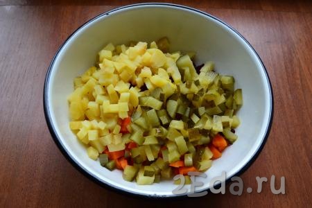 К свекле и моркови добавить очищенный и нарезанный кубиками картофель, нарезанные такими же кубиками маринованные огурцы.