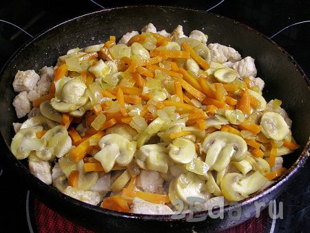 Перекладываем в сковородку с мясом обжаренные лук с морковью и шампиньонами, перемешиваем.