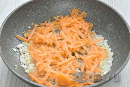 К обжаренному луку выкладываем очищенную морковку, натёртую на крупной тёрке, перемешиваем, и обжариваем овощи 4-5 минут (морковка должна стать мягкой), время от времени помешивая.