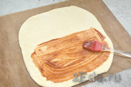 Раскатанное тесто визуально делим на две равные части. Одну часть теста, отступив от краёв 1,5 сантиметра, смазываем томатным соусом (или кетчупом).