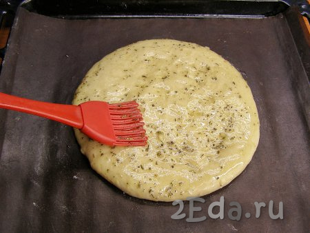 Перекладываем лепёшку на застеленный пекарским ковриком (или бумагой) противень, смазываем тесто маслом, смешанным с травами.