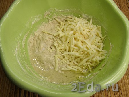 Когда тесто станет достаточно плотным, добавляем в него натёртый на крупной тёрке сыр, растительное масло и соль. Ещё раз перемешиваем ложкой и постепенно, каждый раз полностью вмешивая, добавляем оставшуюся муку.