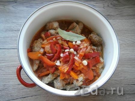 Залить в кастрюлю с кусочками свинины приготовленный соус, добавить нарезанный чеснок и лавровый лист.