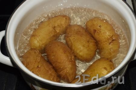 Сложить картофель в кожуре в кастрюлю и полностью залить холодной водой. Поставить кастрюлю на огонь и варить на среднем огне до готовности картошки.
