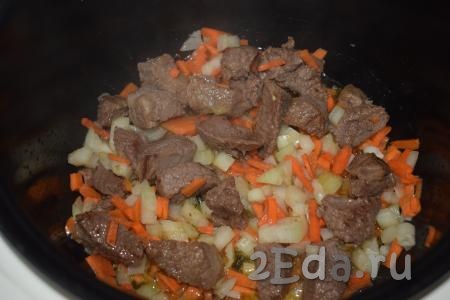 К подрумянившейся говядине добавляем лук и морковь.