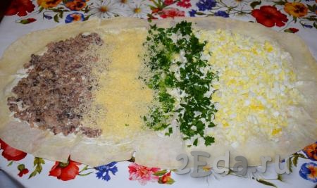 На лаваш, смазанный майонезом, выкладываем полосками рыбу, натертый сыр, измельченные зеленый лук, петрушку и яйца (как на фото).