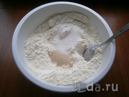 В глубокую посуду всыпать просеянную муку, добавить соль, сахар и сухие дрожжи.