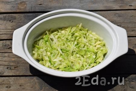 В керамическую форму (или другую форму для выпечки), не смазывая дно маслом, первым слоем равномерно выкладываем половину капусты, смешанной с кабачком.