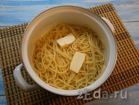 Отварить спагетти, согласно инструкции на упаковке (обычно - это 7-8 минут), затем, откинув на дуршлаг, дать стечь воде и поместить обратно в кастрюлю. Добавить сливочное масло, спагетти перемешать.