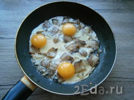 Обжарить лук с салом пару минут, иногда перемешивая, после чего аккуратно вбить яйца, старайтесь, чтобы желтки остались целыми.