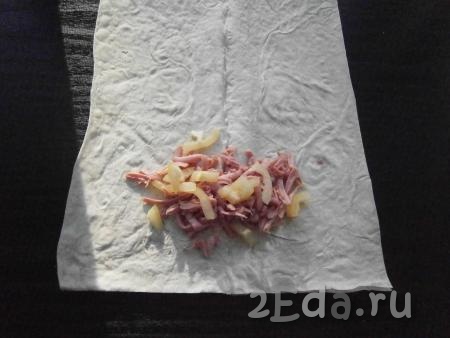Взять одну часть лаваша, на краю разместить 1-2 столовые ложки колбасы и немного нарезанного болгарского перца (как на фото).