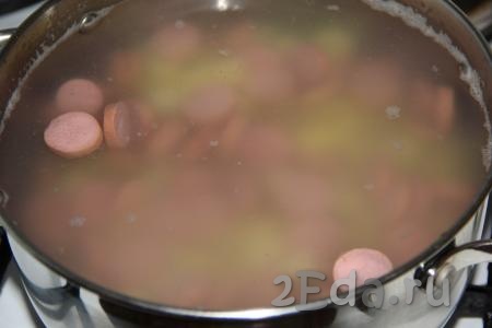 Затем сосиски нарезать на кружочки и выложить в кастрюлю с картошкой, варить 10 минут.