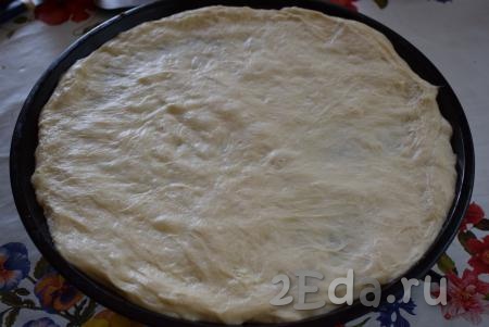 Готовое дрожжевое тесто слегка вымешиваем. Начинаем формировать луковый пирог, для этого форму для выпечки смазываем растительным маслом и выкладываем тесто на дно формы. Распределяем тесто руками по размеру формы (у меня форма диаметром 34 см).