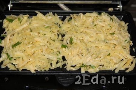 Вафельницу хорошо разогреть и смазать растительным маслом. Выложить по 2 столовые ложки картофельной массы на каждую сторону и равномерно распределить по поверхности.