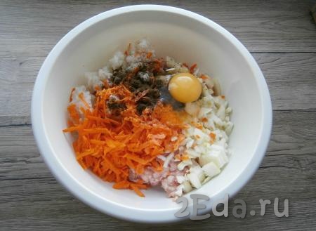 К фаршу, рису и луку добавить натертую на крупной терке очищенную морковь, сырое яйцо, соль и черный молотый перец, перемешать.