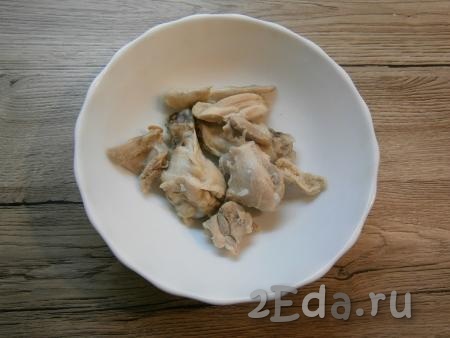 Отваренную курицу выложить в тарелку, остудить, отделить мясо от костей и нарезать на небольшие кусочки.