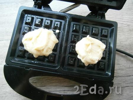 Электровафельницу, предназначенную для толстых вафель, разогреть, смазать немного растительным маслом, выложить в ячейки по 1-2 столовых ложки теста.