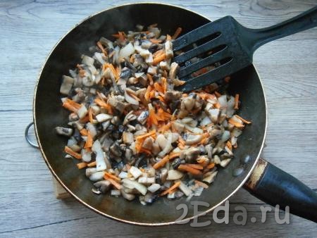 Добавить очищенную и натертую на крупной терке морковь, обжаривать овощи с грибами минут 5 на среднем огне, иногда помешивая, а затем еще 5-7 минут на небольшом огне. Выделившаяся из грибов жидкость должна полностью испариться.