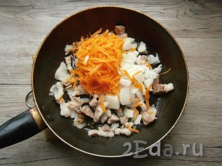 На сковороду с грудинкой (или на сухую сковороду, если готовите без грудинки) влить растительное масло, добавить нарезанный произвольно репчатый лук и натертую на крупной терке морковь.