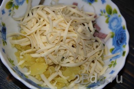 Сыр натереть на тёрке и добавить в начинку из картошки, зелени и ветчины.