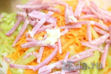 Перец, колбасу и очищенный чеснок, пропущенный через пресс, добавить в салат из капусты и моркови.