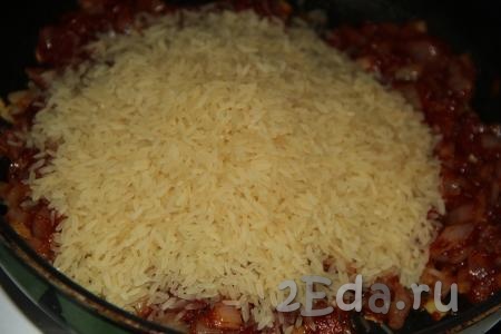 Обжаренный лук перемешать с томатной пастой, затем всыпать рис. Я использовала пропаренный рис, если будете брать белый рис, тогда его нужно предварительно хорошо промыть.