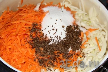 Морковь очистить и натереть на крупной тёрке. Добавить натёртую морковь, соль и тмин в кастрюлю к капусте.