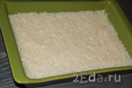 В жаропрочную форму (форму можно предварительно не смазывать маслом) выложить отваренный рис и разровнять.