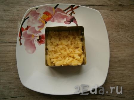 На тарелку с помощью кольца выкладывать салат слоями. Очищенный и нарезанный небольшими кубиками вареный картофель выложить первым слоем, немного посолить.