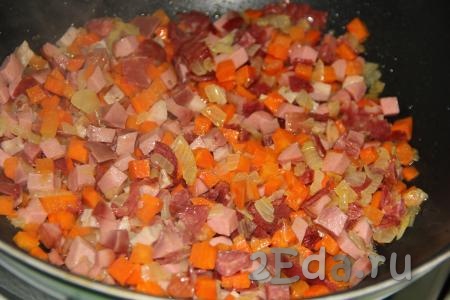 Обжарить овощи с колбасой в течение 10 минут на небольшом огне, помешивая (если вы готовите без добавления колбасных изделий, тогда обжаривайте овощи, помешивая, до мягкости моркови).