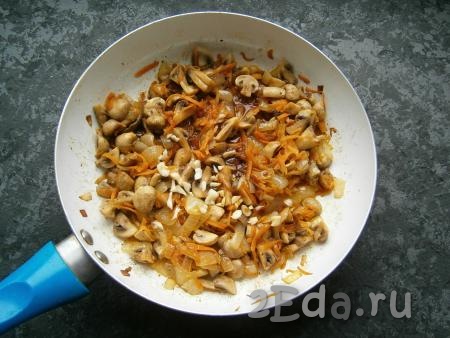 Обжаривать грибы с морковкой и луком на среднем огне, помешивая, около 5 минут, затем влить соевый соус, добавить нарезанный чеснок.