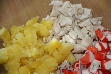 Картошку, сваренную в мундире, остудить, очистить, нарезать на кубики среднего размера и выложить к нарезанному куриному мясу.
